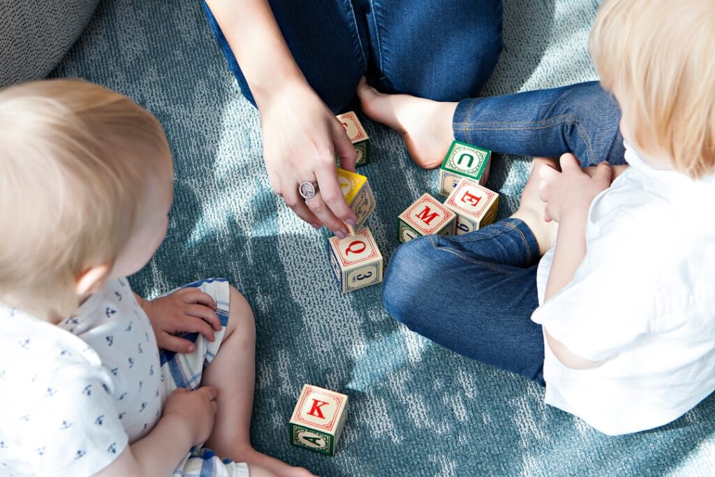 Young children playing together with blocks and art supplies on a colorful classroom floor.