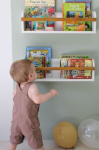 A cozy, well-lit corner of a living room set up with toddler-sized furniture, books, and toys neatly organized on low shelves.