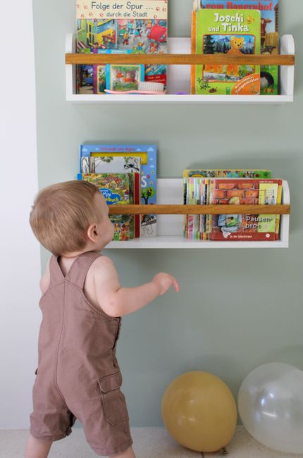 A cozy, well-lit corner of a living room set up with toddler-sized furniture, books, and toys neatly organized on low shelves.