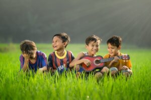 Young children singing and playing with simple hand instruments together in a colorful classroom.